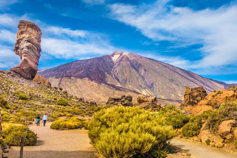 Panoramic view of unique Roque Cinchado unique rock formation with famous Pico del Teide mountain volcano summit in the background on a sunny day, Teide National Park, Tenerife, Canary Islands, Spain