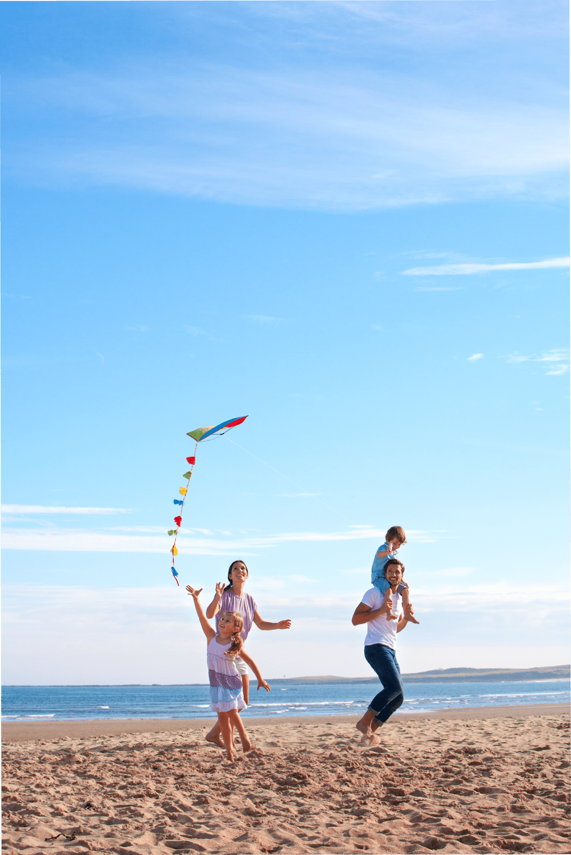 Family of four flying a kite together on the beach