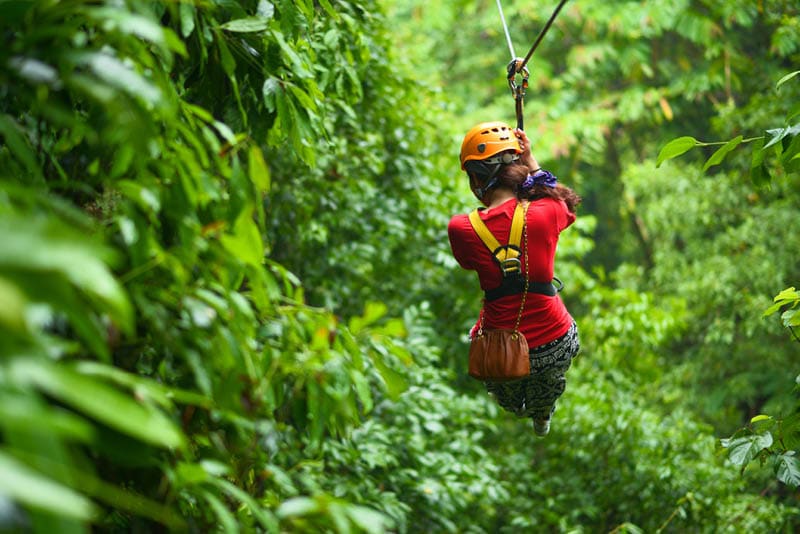 An explorer is moving on cableway in the rainforest