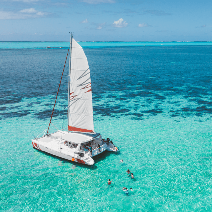 Family and friends swimming near a beautiful catamaran in the paradise turquoise lagoon of the east coast of Mauritius