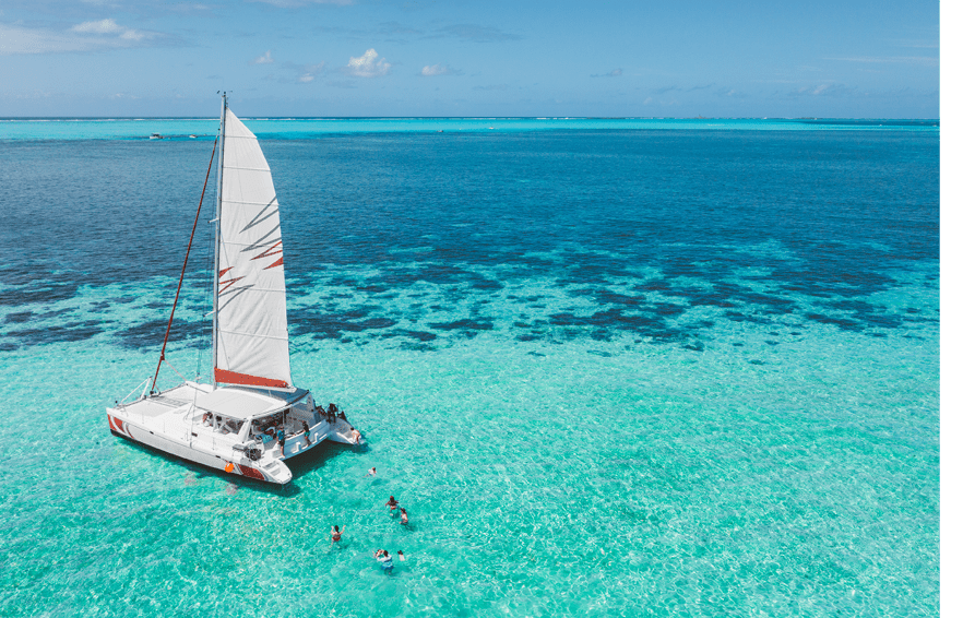 Family and friends swimming near a beautiful catamaran in the paradise turquoise lagoon of the east coast of Mauritius