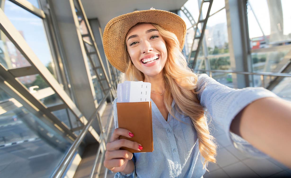 Enjoy traveling. Beautiful woman taking selfie in airport, waiting for boarding
